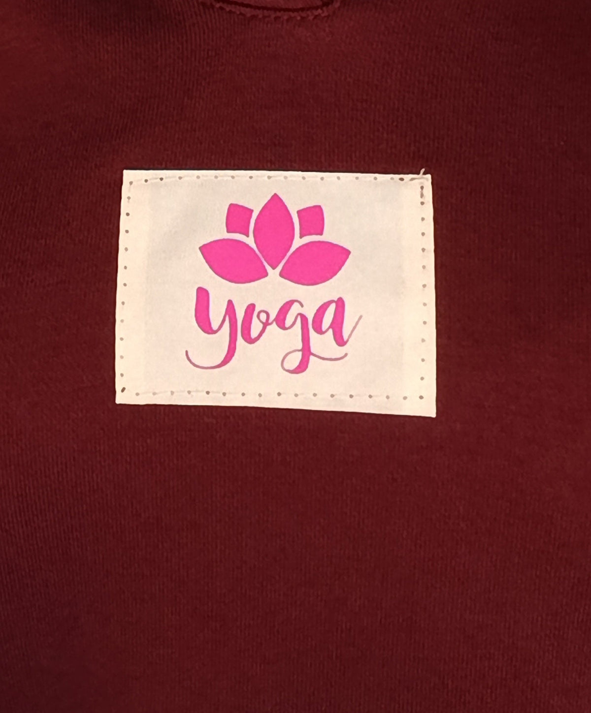 Detailaufnahme des Yoga-Lotus-Labels auf einem bordeauxfarbenen Hoodie
