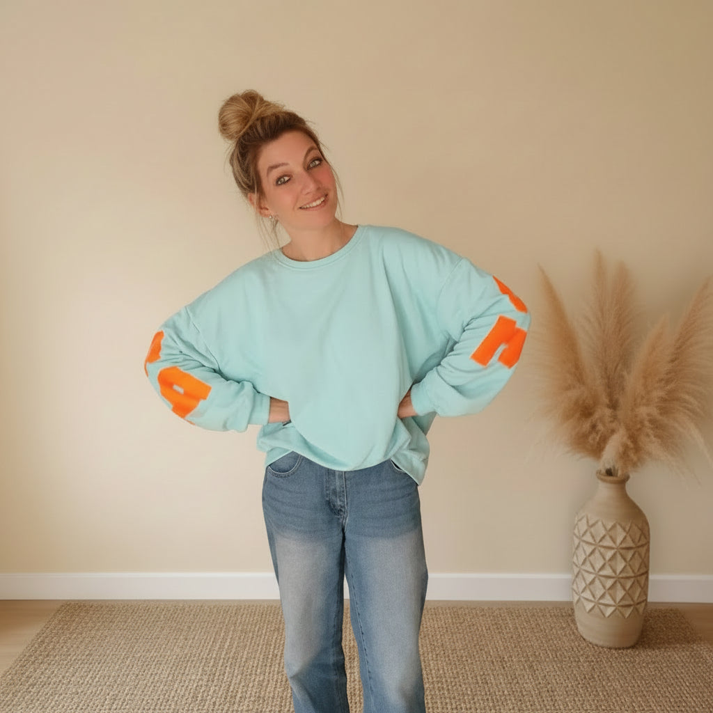 Frau in hellblauem PARADISE Sweatshirt von SK-Style & Kompetenz aus weichem Material im Boho-Luxe Style.