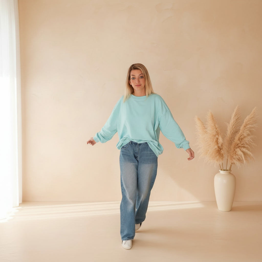 Frau in hellblauem PARADISE Sweatshirt von SK-Style & Kompetenz und Jeans im Boho-Luxe Stil.