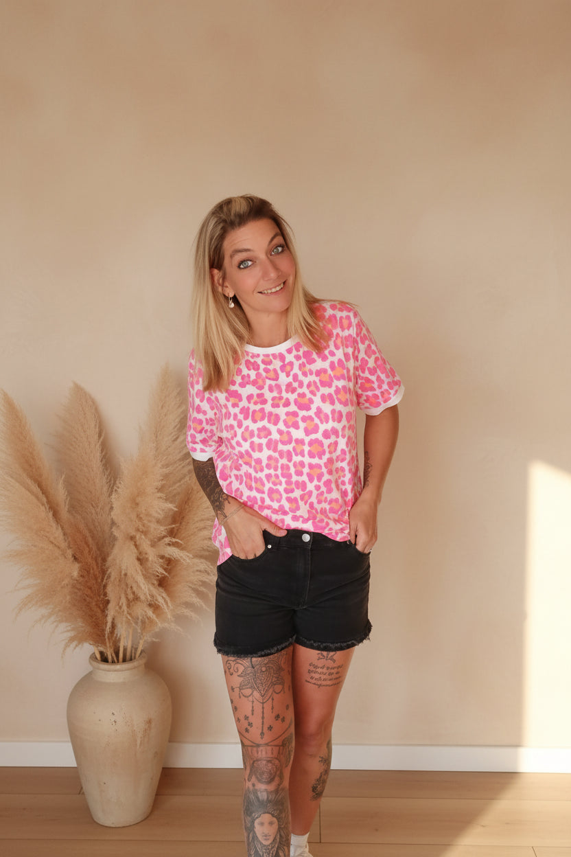 Boho-Luxe Damenmode: Rosa T-Shirt mit Leopardenmuster aus weichem Stoff und schwarze Shorts.