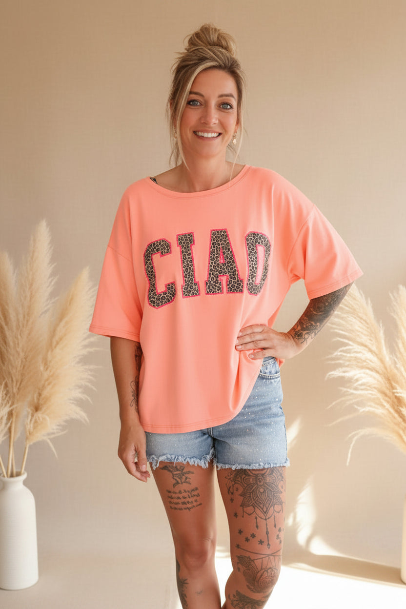 Boho-Luxe Style: Korallenfarbenes Oversize-T-Shirt mit Leopardenprint und hellblaue Jeansshorts.