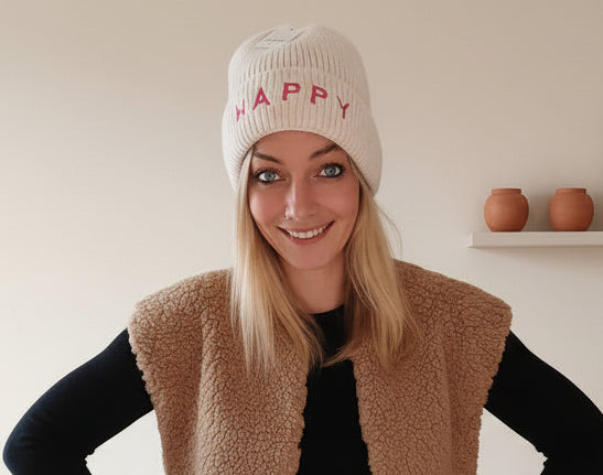 Damen-Strickmütze HAPPY in Creme mit rotem Schriftzug, Frontansicht im lässigen Winter-Outfit