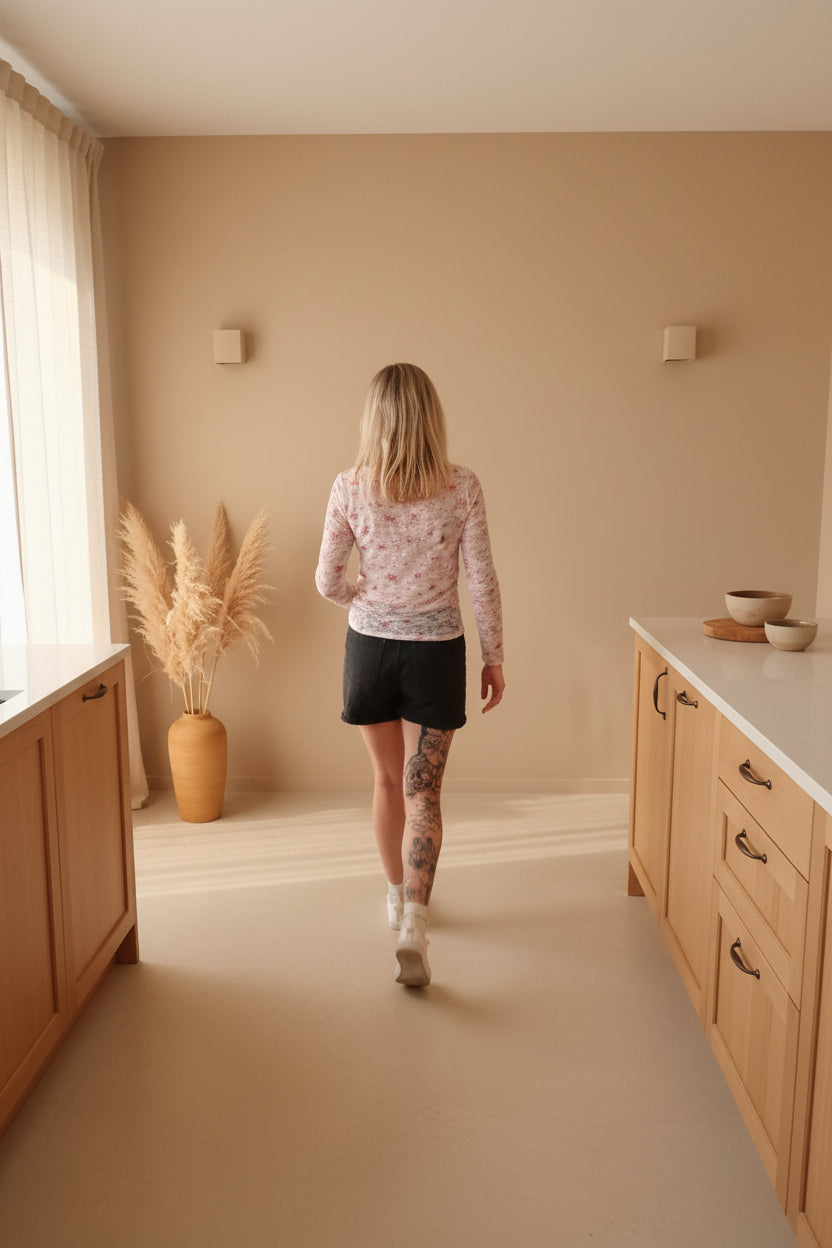 Boho-Luxe Style: Frau in rosa gemustertem Langarmshirt und schwarzem Rock.