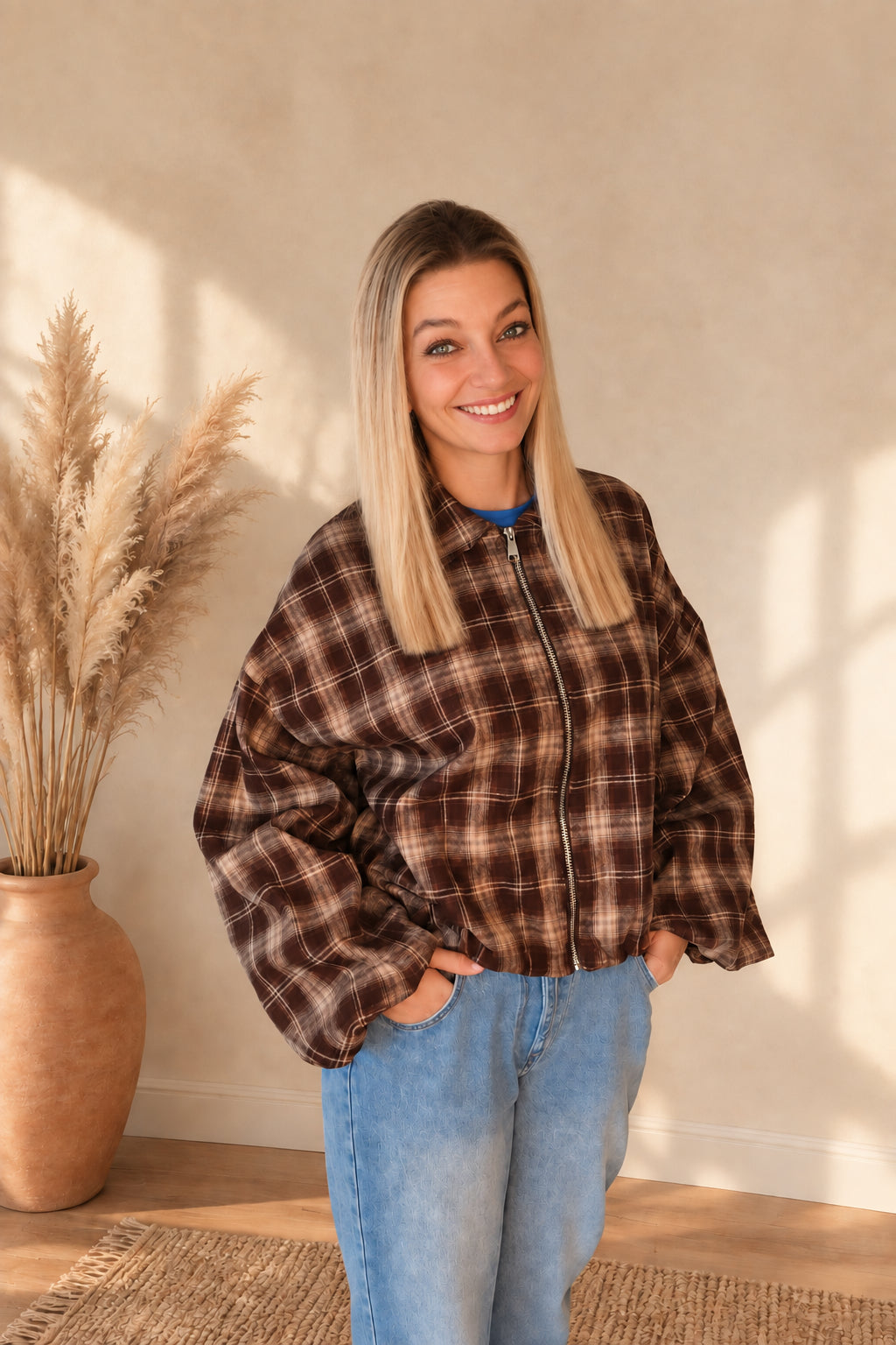 Geschlossene karierte Damenjacke in Dunkelbraun und Beige mit Reißverschluss, Model mit Händen in den Jeanstaschen.