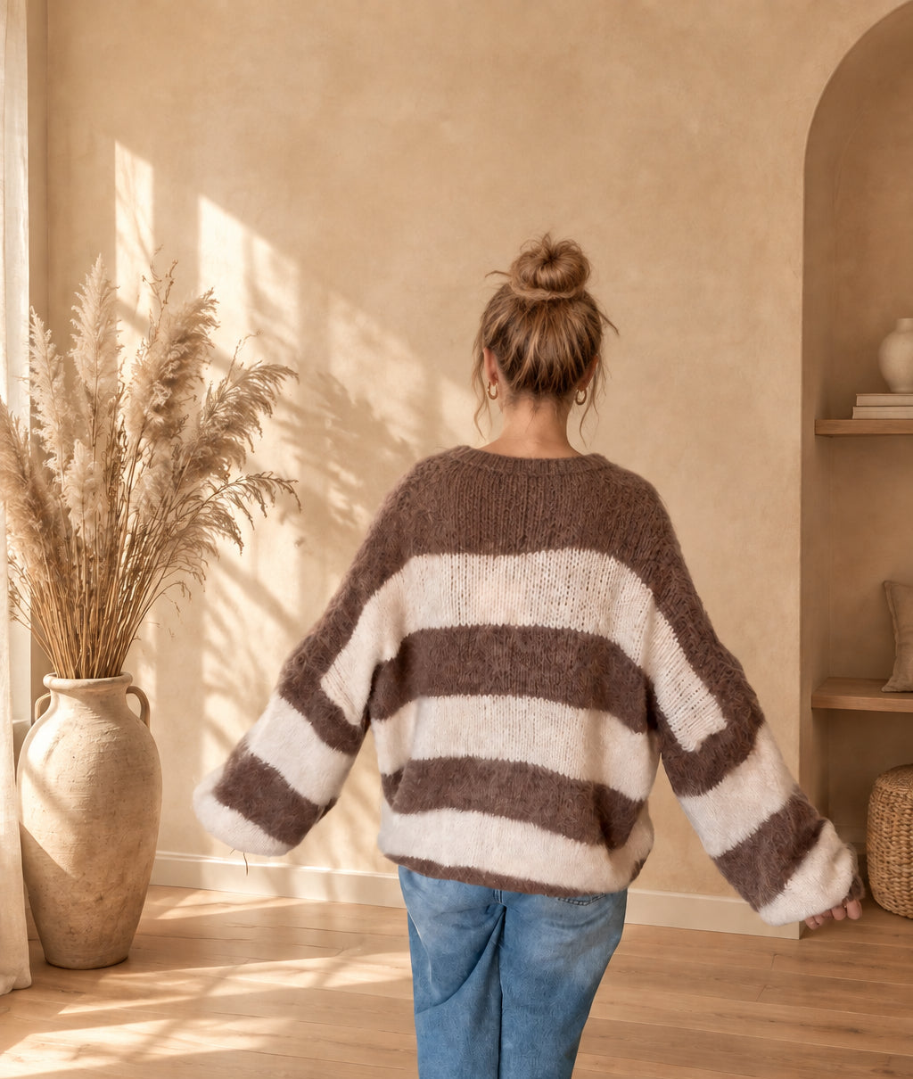 Rückansicht der taupe-creme gestreiften Damen-Strickjacke mit lockerem Schnitt, am Model mit ausgestreckten Armen.