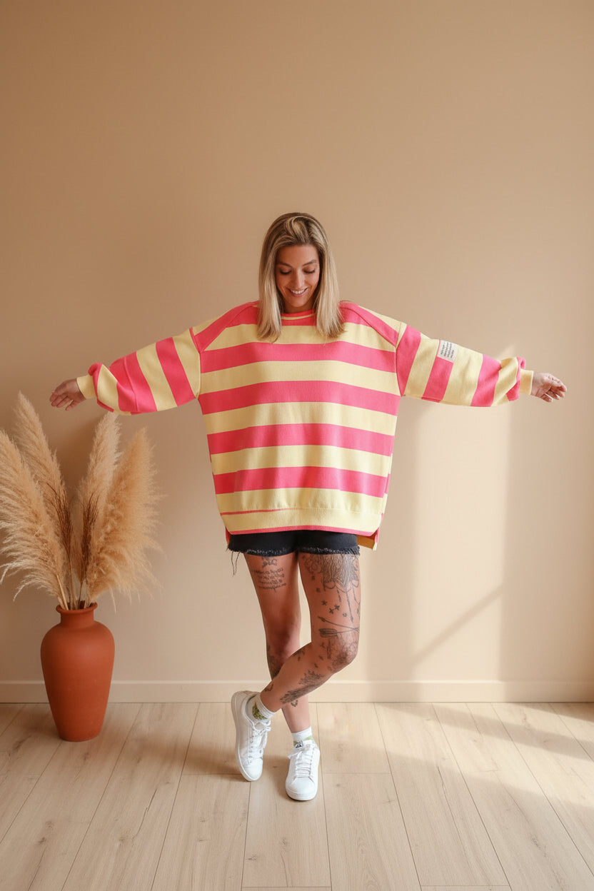 Boho-Luxe Damenmode: Rosa-gelb gestreifter Oversize-Pullover aus weichem Material.