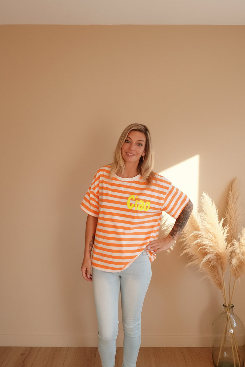Boho-Luxe Look: Orange-weiß gestreiftes T-Shirt aus Baumwolle und helle Jeans.