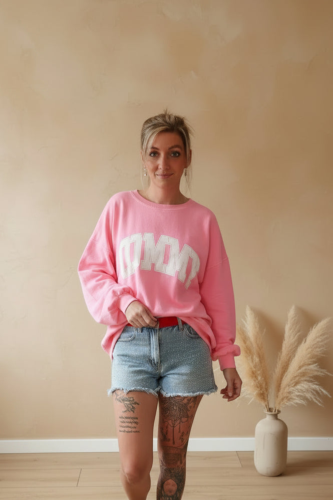 Boho-Luxe Look: Rosa Sweatshirt mit weißem Print und hellblaue Denim-Shorts.