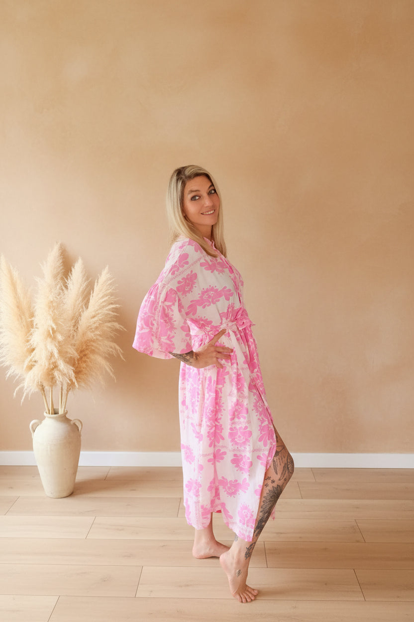 Blossom Kleid Rosa Seitenansicht – Lächelnder Blick über Schulter, rosa Blumenkleid mit Bindegürtel