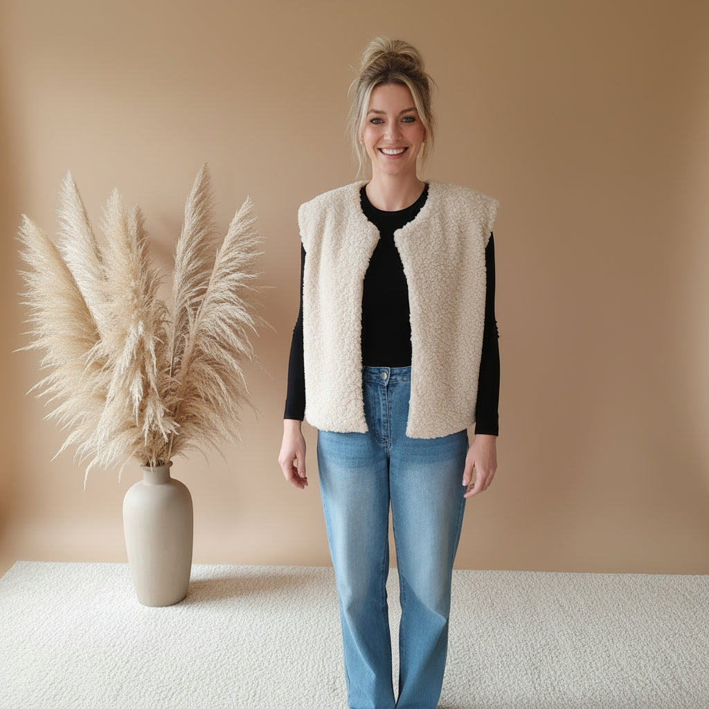 Cremefarbene Teddyfell-Weste für Damen in stilvoller Frontansicht, offen getragen zu schwarzem Langarmshirt und Jeans