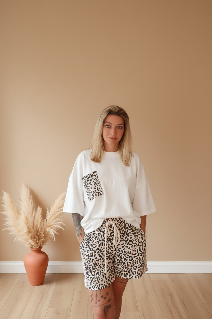 Boho-Luxe Outfit: Weißes Baumwoll-T-Shirt mit Leopardenprint-Tasche und passenden Shorts.