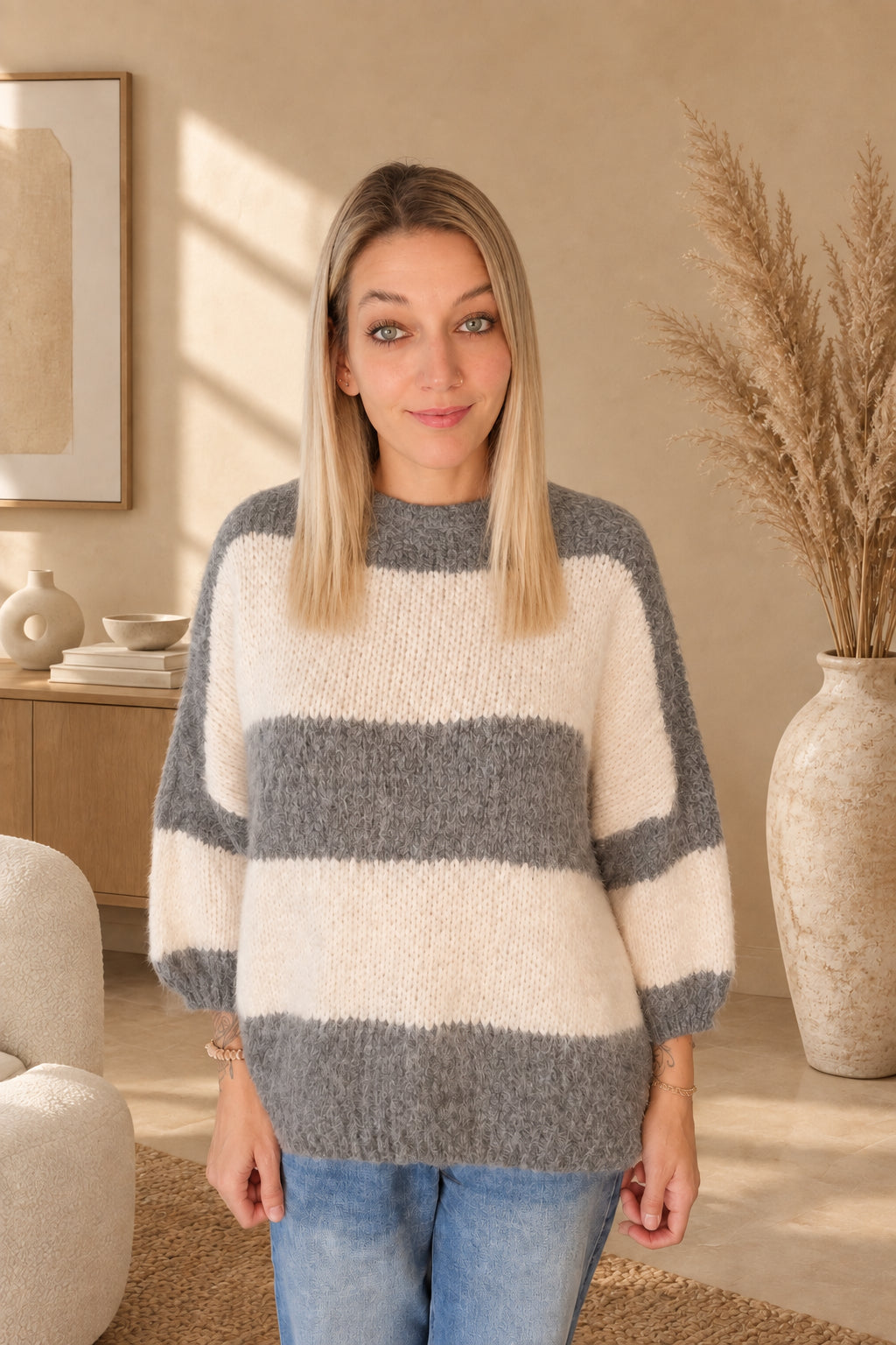 Vorderansicht des Damen-Strickpullovers mit breiten grau-cremeweißen Querstreifen und geripptem Saumbündchen.
