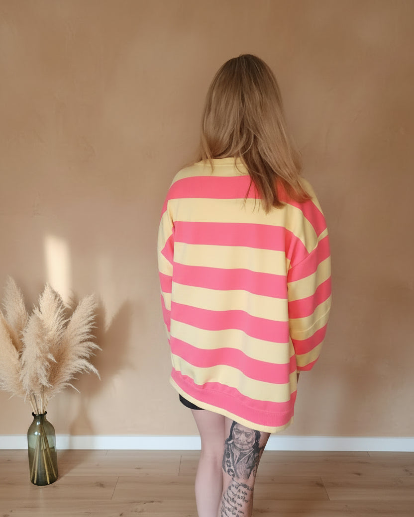 Boho-Luxe Damenmode: Oversize-Sweatshirt mit rosa und gelben Querstreifen aus weichem Stoff.