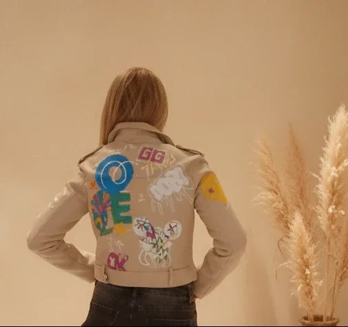 Beige Lederjacke für Damen im Boho-Luxe Stil mit farbenfrohen Graffiti-Prints auf der Rückseite.