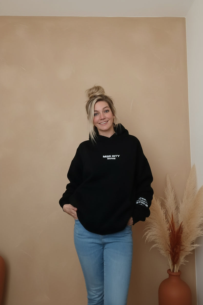Schwarzer Boho-Luxe Kapuzenpullover aus Baumwolle kombiniert mit hellblauen Jeans.