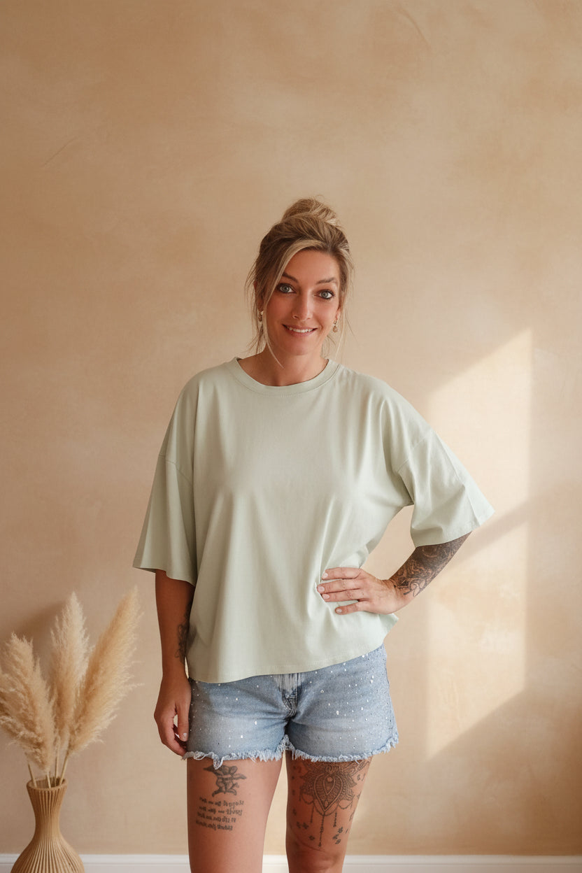 Mintgrünes Oversize T-Shirt Self Love, Frontansicht im warmen Sonnenlicht, Boho-Luxe Editorial Look