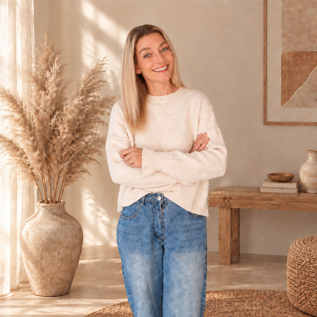 Model trägt einen hellen Damenpullover mit Rundhalsausschnitt zu Jeans und verschränkt die Arme.