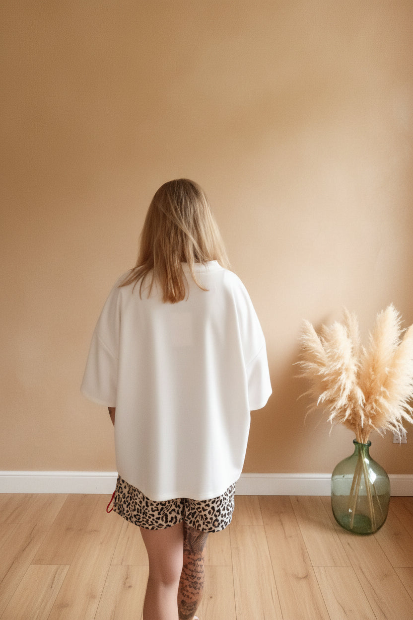 Boho-Luxe Style: Weißes Oversize-Shirt aus Baumwolle und Leopard-Shorts vor beigem Hintergrund.