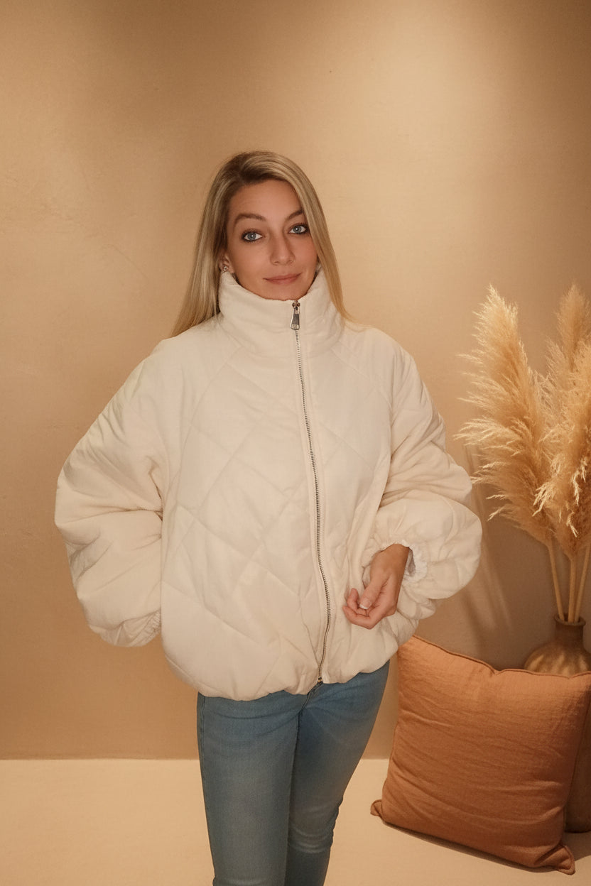 Frau in weißer, gesteppter Boho-Luxe Jacke aus weichem Material und blauen Jeans