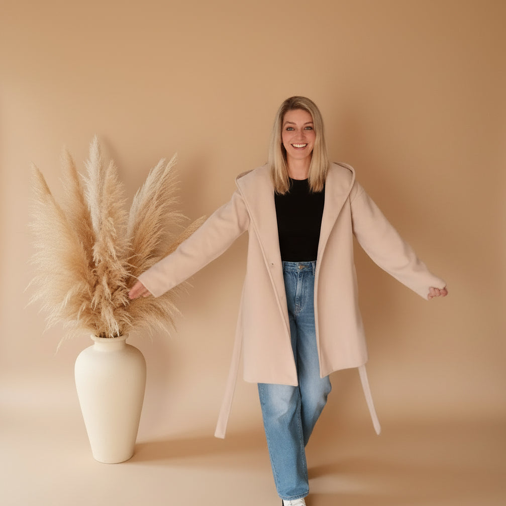 Cremeweißer Damen-Kurzmantel mit Kapuze und Bindegürtel in der Frontansicht, kombiniert mit Jeans