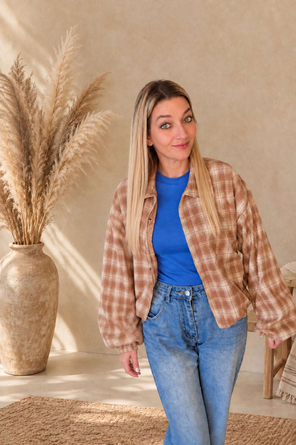 Kurze karierte Damenjacke in Braun und Creme, offen über einem blauen Shirt zu Jeans getragen.