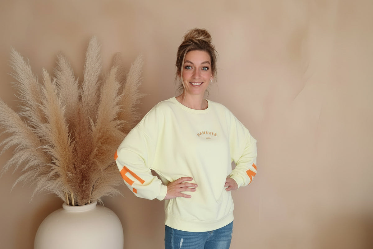 Namasté Oversize Sweatshirt Damen Pastellgelb Neonorange – Frontansicht Hände in Hüften lächelnd Boho Setting