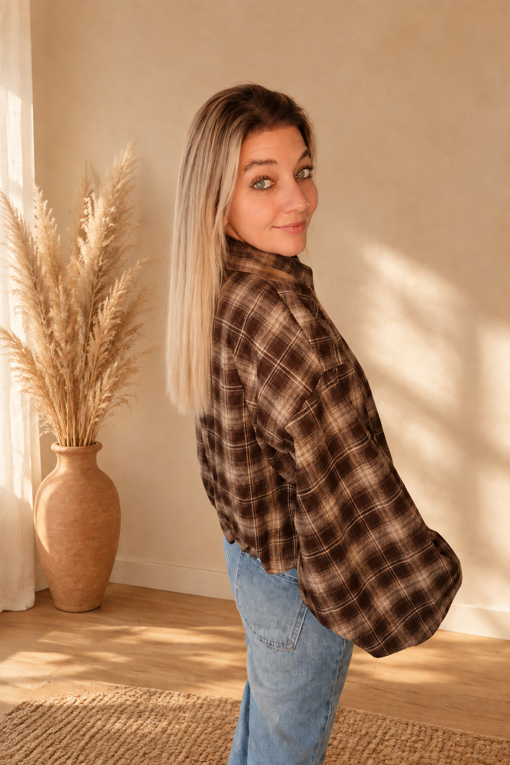 Karierte Damenjacke in Dunkelbraun und Beige in schräger Rückansicht mit weitem Ärmel und kurzem Saum.