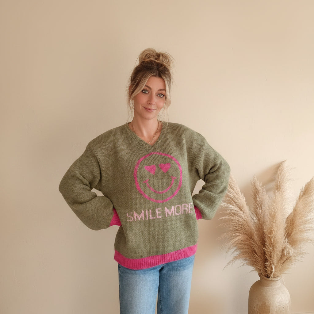 Zwillingsherz Smile-More-Strickpullover in Olivgrün mit pinkem Smiley, Model mit Händen in der Taille