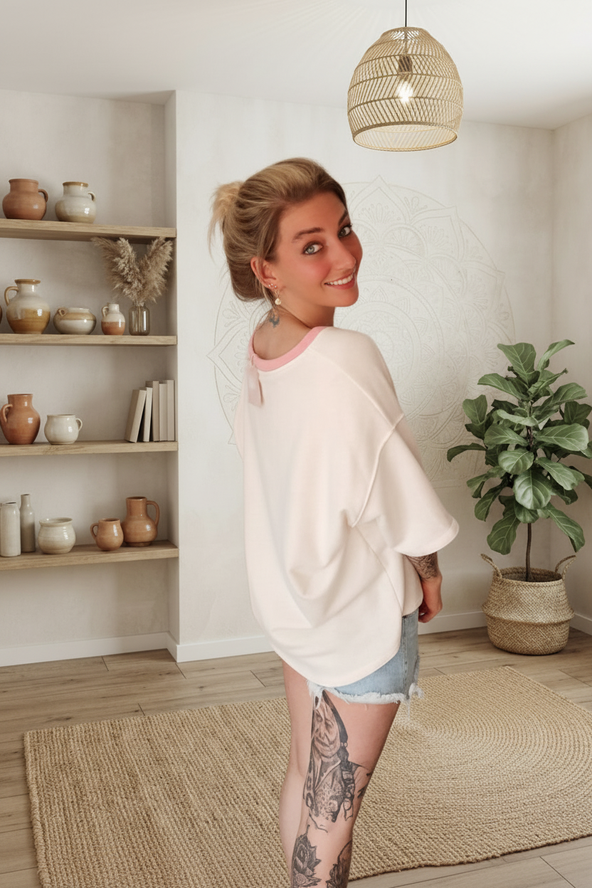 Moderne Frau in hellem, weichem Oversize-Shirt und Jeansshorts im Boho-Luxe-Stil.