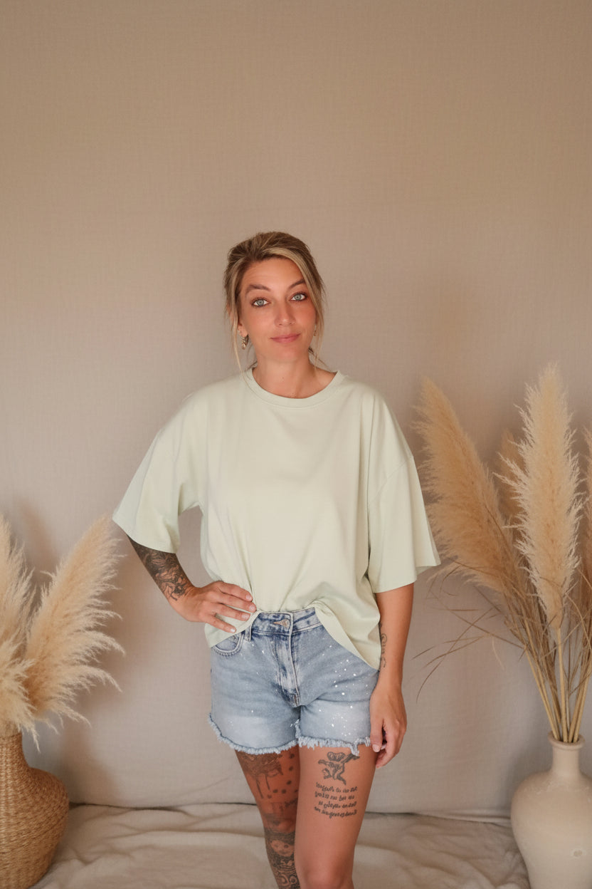 Mintgrünes Oversize T-Shirt Self Love, Frontansicht, Boho-Luxe Styling mit Jeans-Shorts und Pampas-Deko