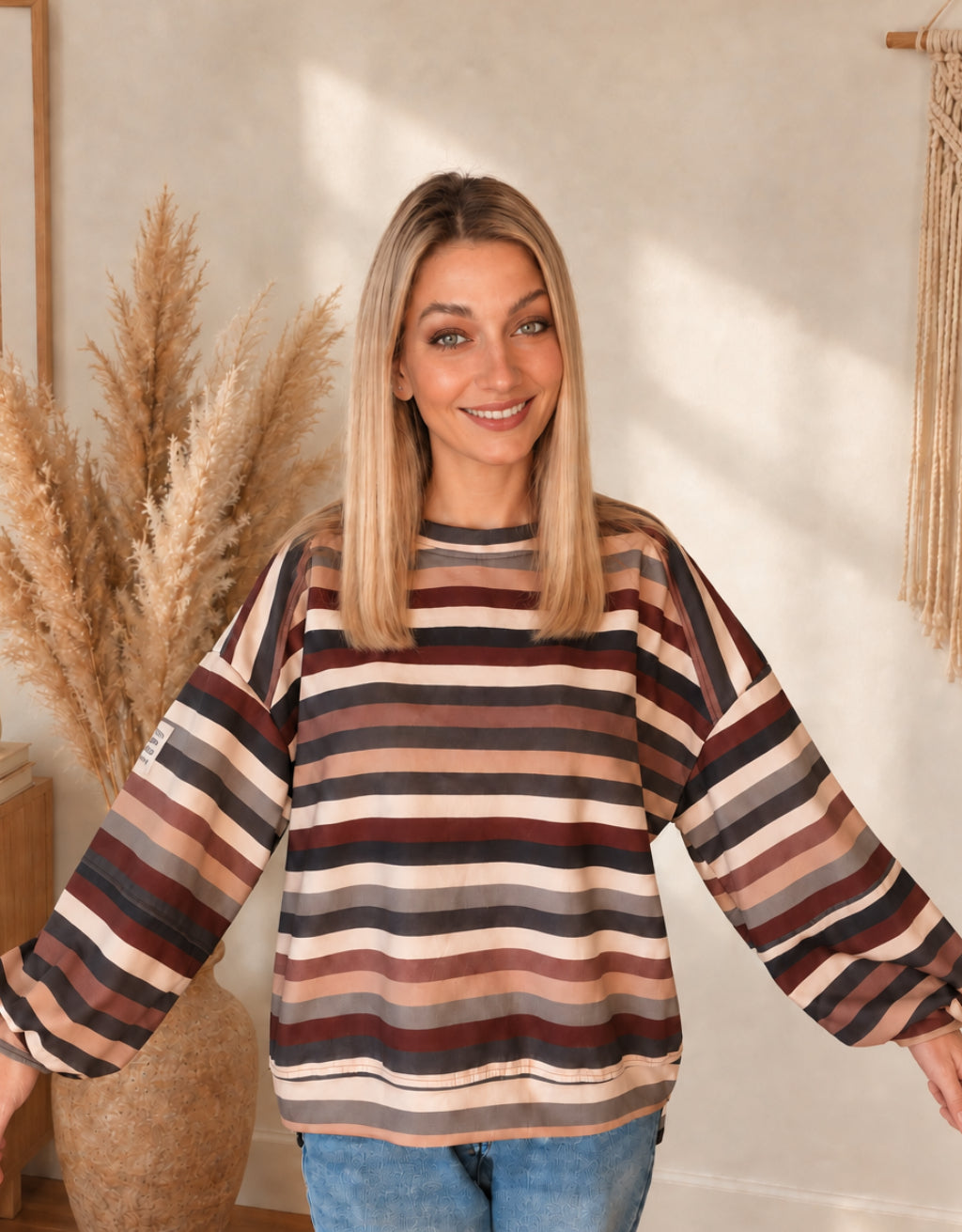Damen-Streifenoberteil in Braun, Creme und Grau mit lockerem Schnitt und weiten langen Ärmeln, frontal am Model mit ausgestreckten Armen.