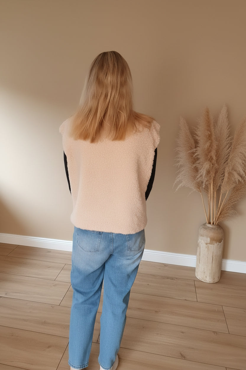 Rückansicht der cremefarbenen Damen-Teddyfell-Weste mit weicher Teddyfell-Oberfläche, schwarzem Oberteil und Jeans