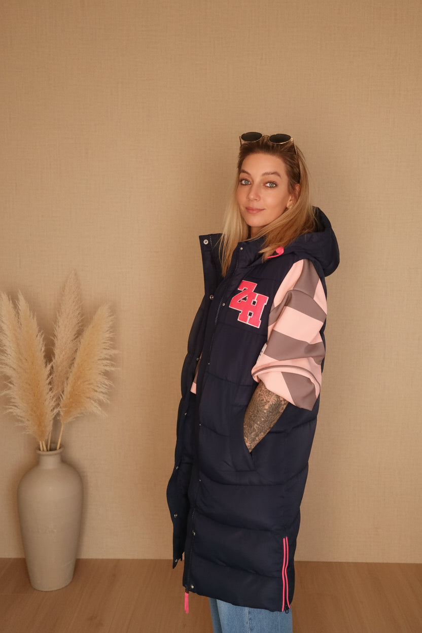 Frau in dunkelblauer Steppjacke mit rosa Streifen und Ziffern im Boho-Luxe Stil