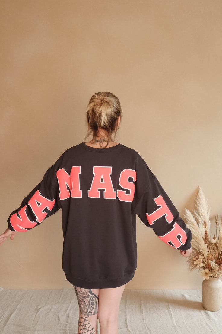 Boho-Luxe schwarzer Sweatshirt aus Baumwolle mit pinkem Namaste-Schriftzug auf dem Rücken.
