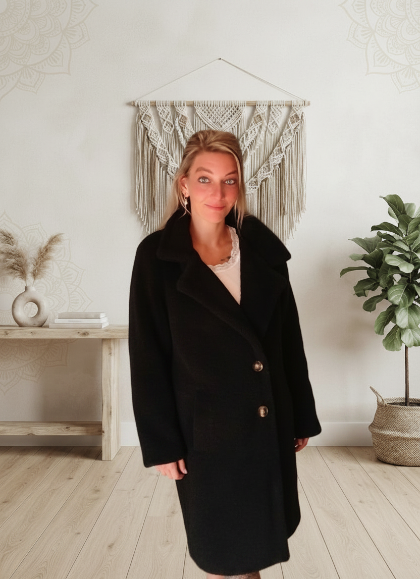 Teddy-Mantel Damen in Schwarz – Frontansicht mit Reverskragen, Boho-Interieur mit Pflanze