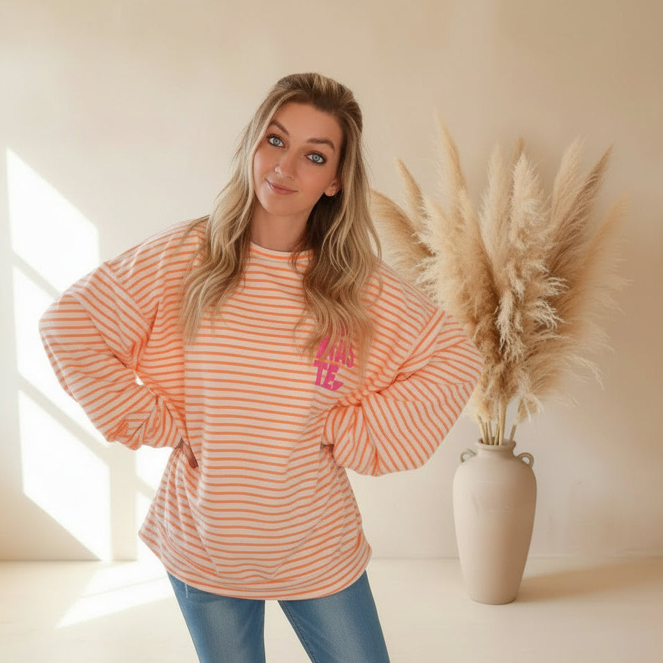Nahaufnahme des peach-weiß gestreiften Damen-Sweatshirts mit pinkem NAMASTE-Print auf der Brus