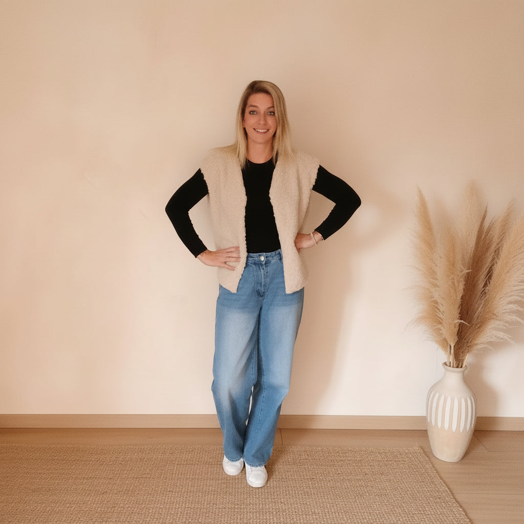 Cremefarbene Teddyweste im modernen Frontlook mit schwarzem Oberteil, Jeans und weißen Sneakern, ideal für den Alltag