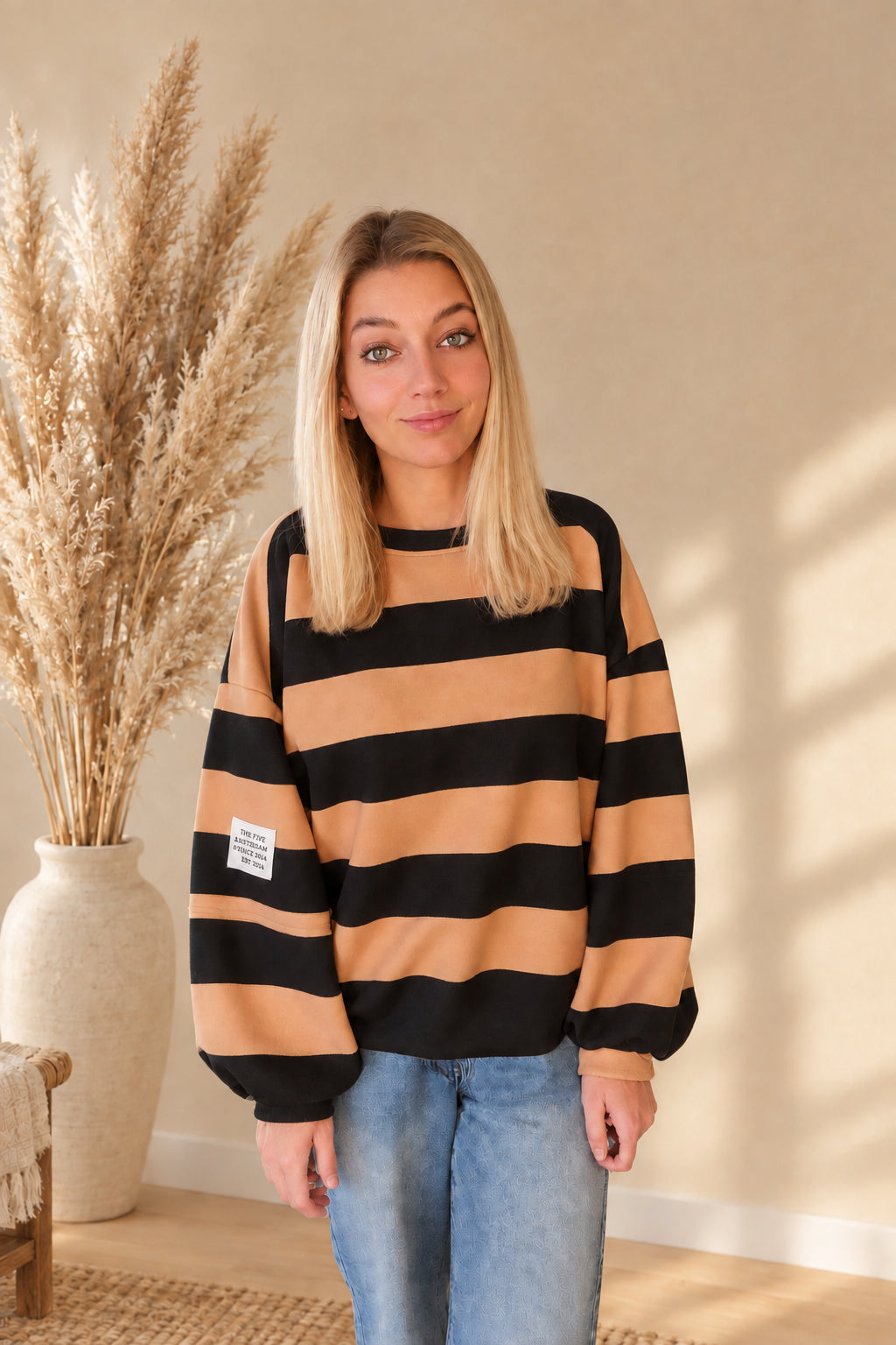 Damen-Sweatshirt in Camel und Schwarz mit lockerem Schnitt und langen Ärmeln, am Model mit gesenkten Armen.