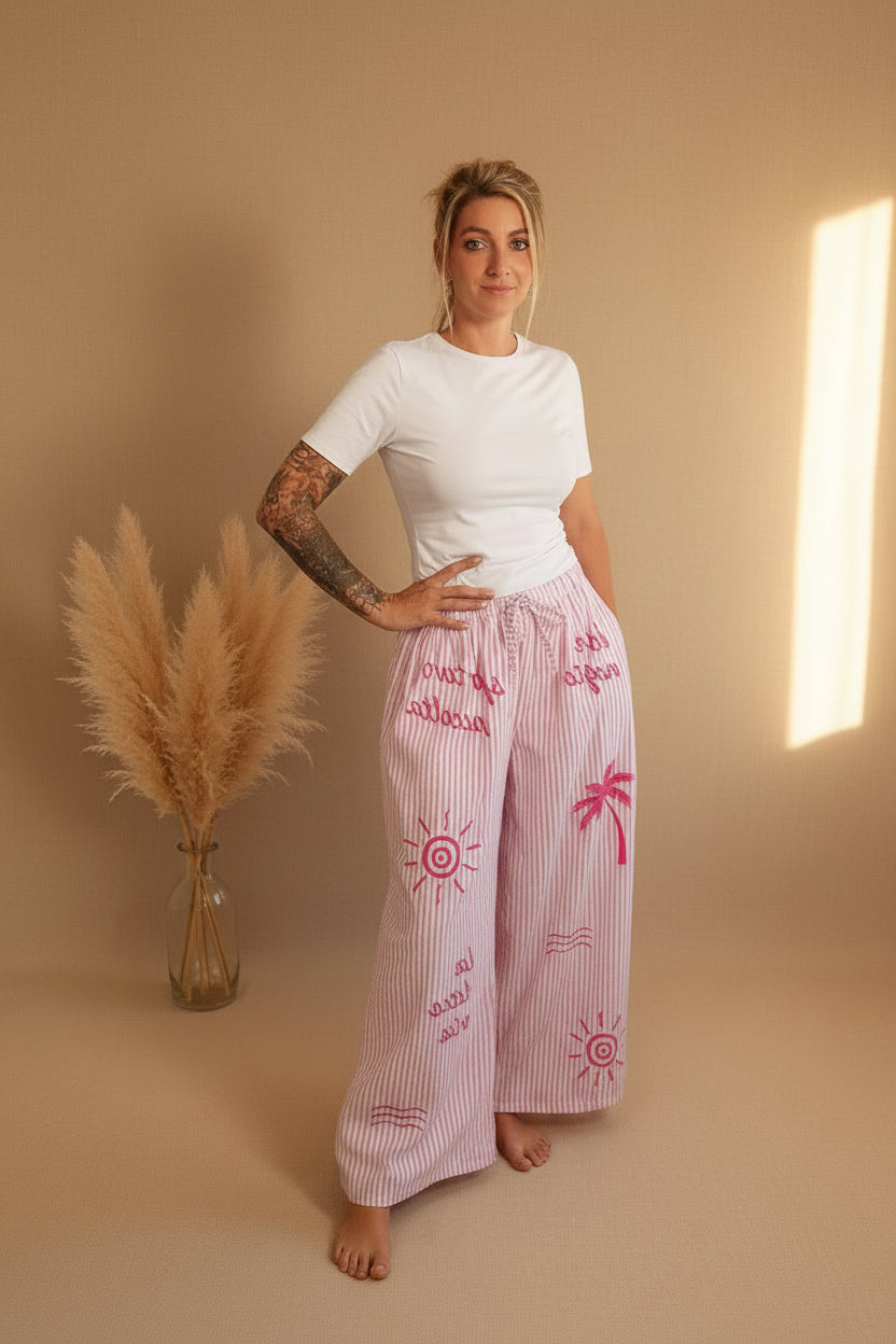Boho-Luxe Look: Weiße Baumwoll-T-Shirt und rosa gestreifte Leinenhose mit Palmen-Print.