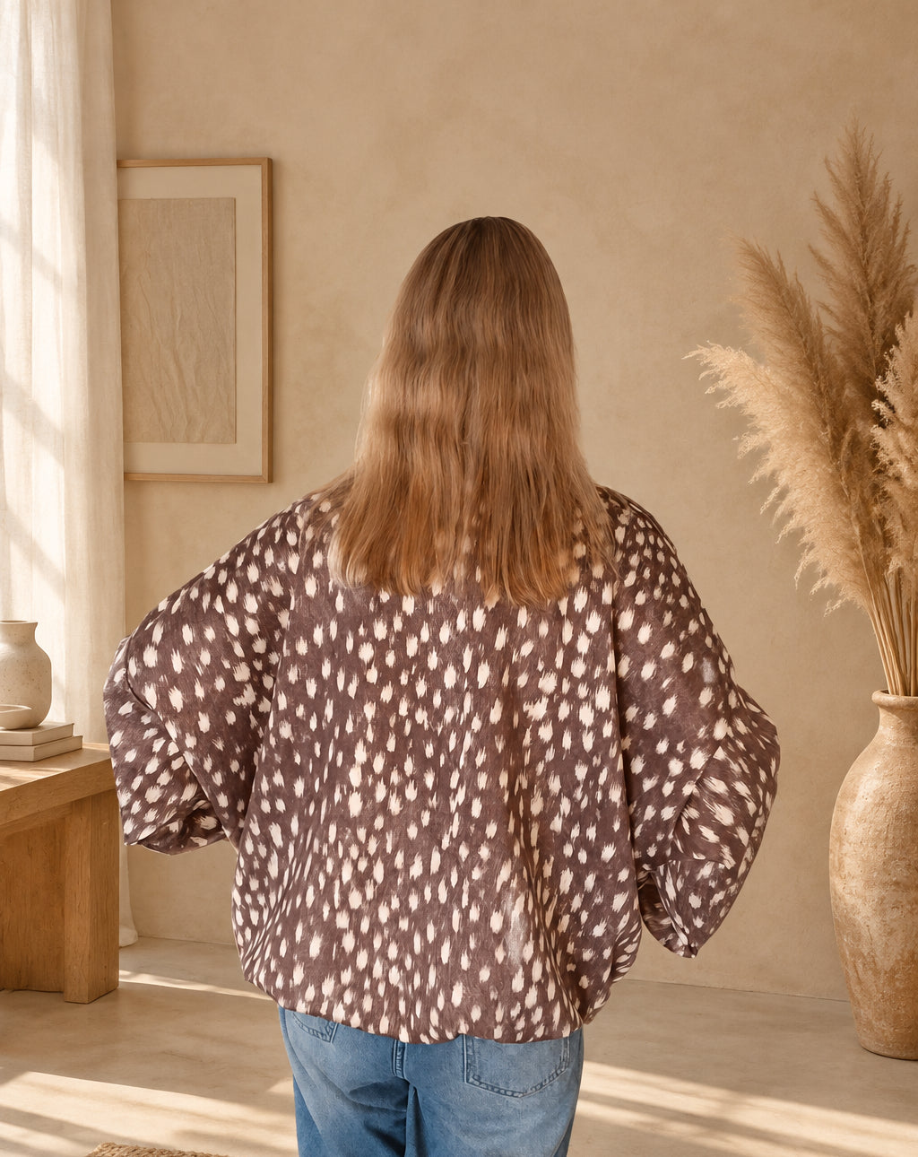 Braune Damenjacke mit cremefarbenem Fleckenmuster von hinten, am Model mit Händen an der Hüfte.