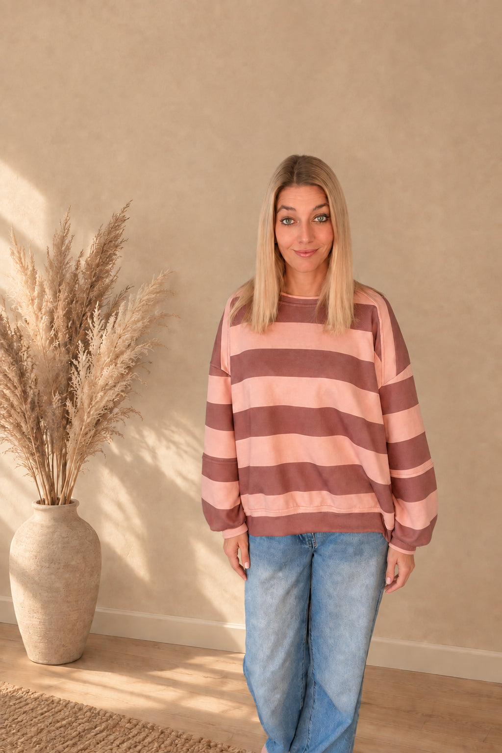 Damen-Sweatshirt in Rosa und Braun von vorne, mit langen Ärmeln und lockerem Sitz über einer blauen Jeans.