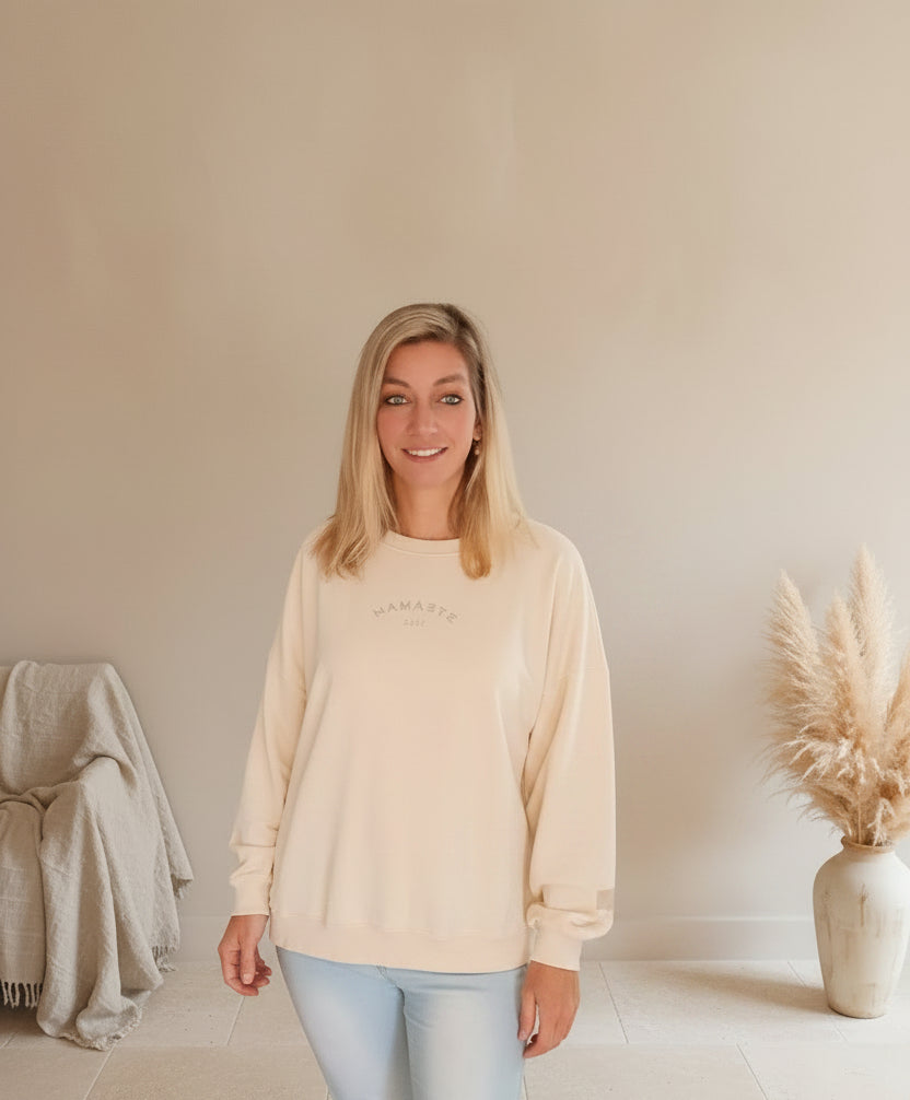Namaste 24/7 Oversized Sweatshirt Creme – Frontansicht mit goldenem Namaste-Logo, kombiniert mit Jeans