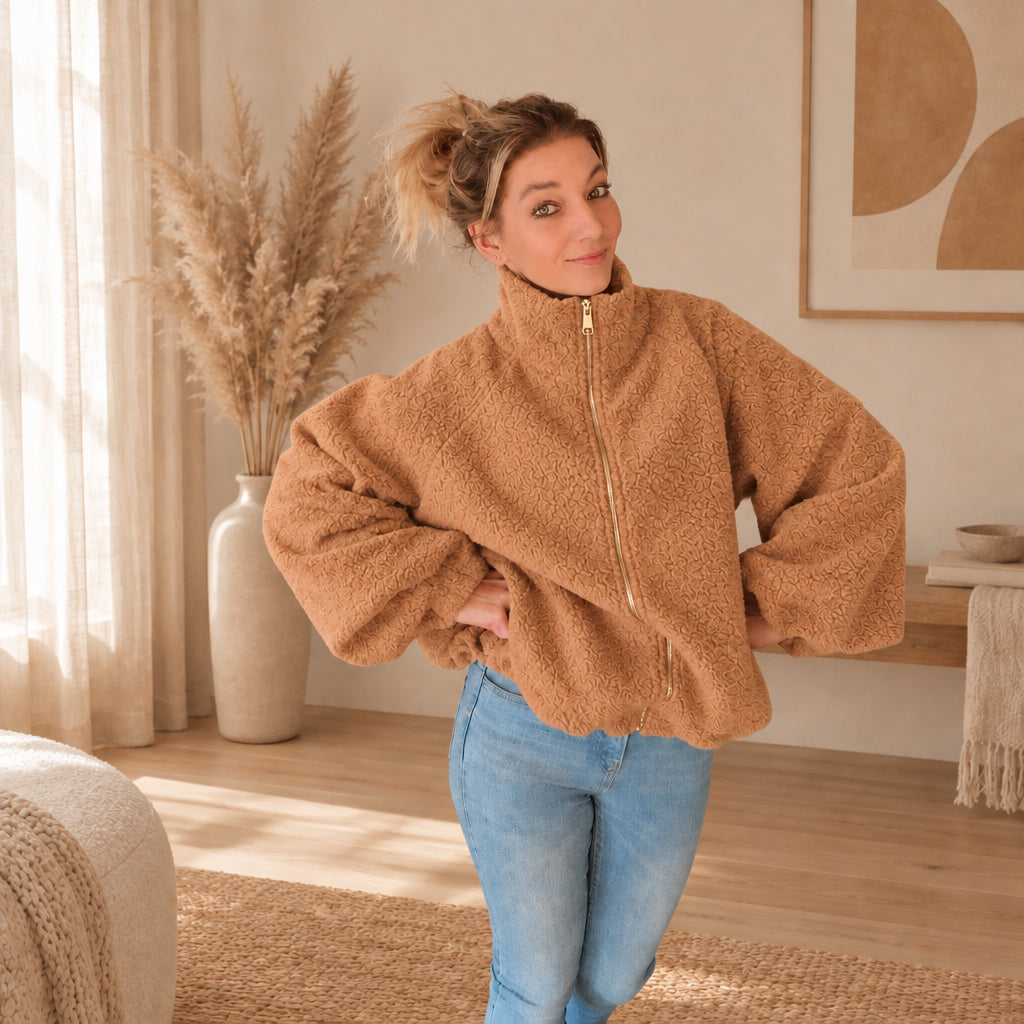 Karamellbraune Teddyjacke mit Stehkragen und weiten Ärmeln, Frontansicht mit Händen an der Hüfte