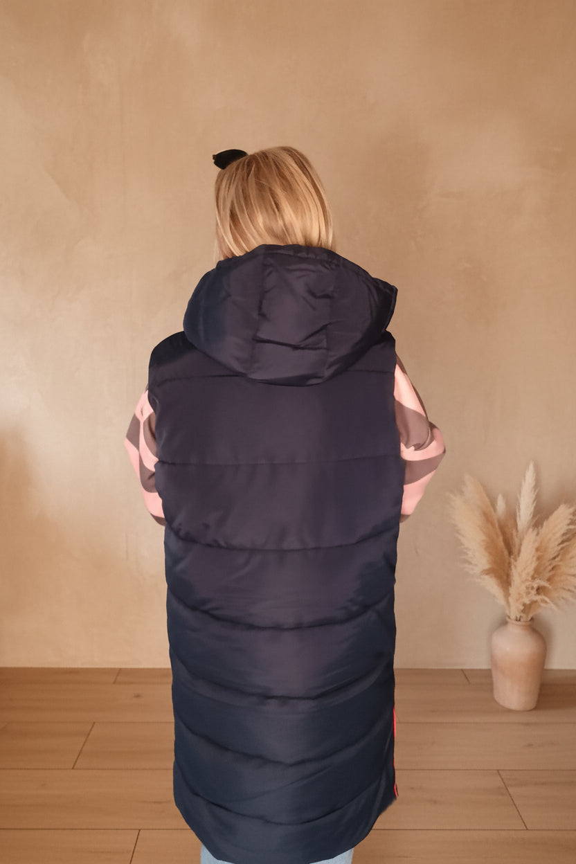 Rückansicht einer dunkelblauen Steppweste mit Kapuze aus glänzendem Material im Boho-Luxe Stil.
