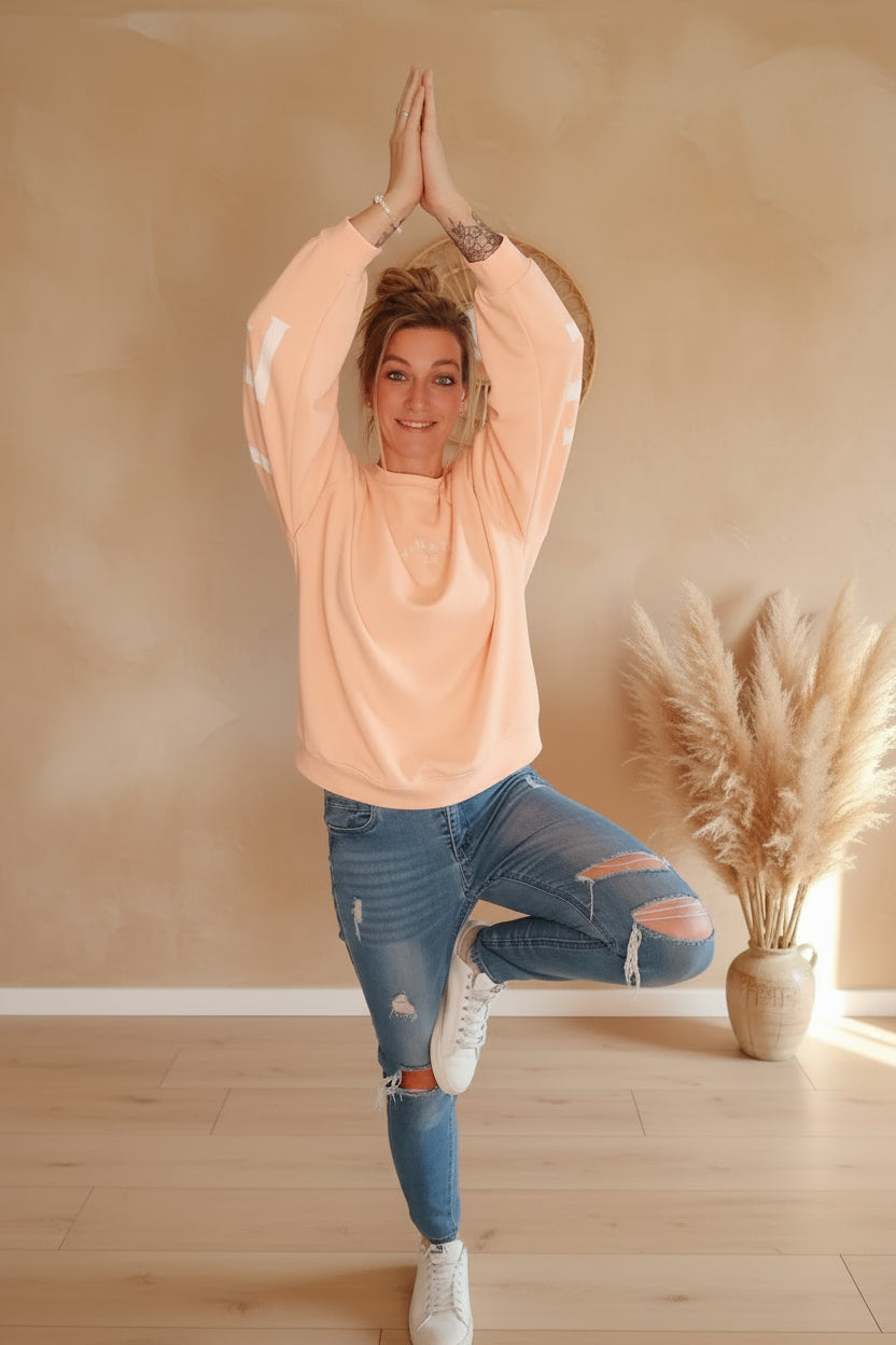 Damen Namasté Sweatshirt in Peach mit weißem Ärmelprint, lässig zu Jeans kombiniert