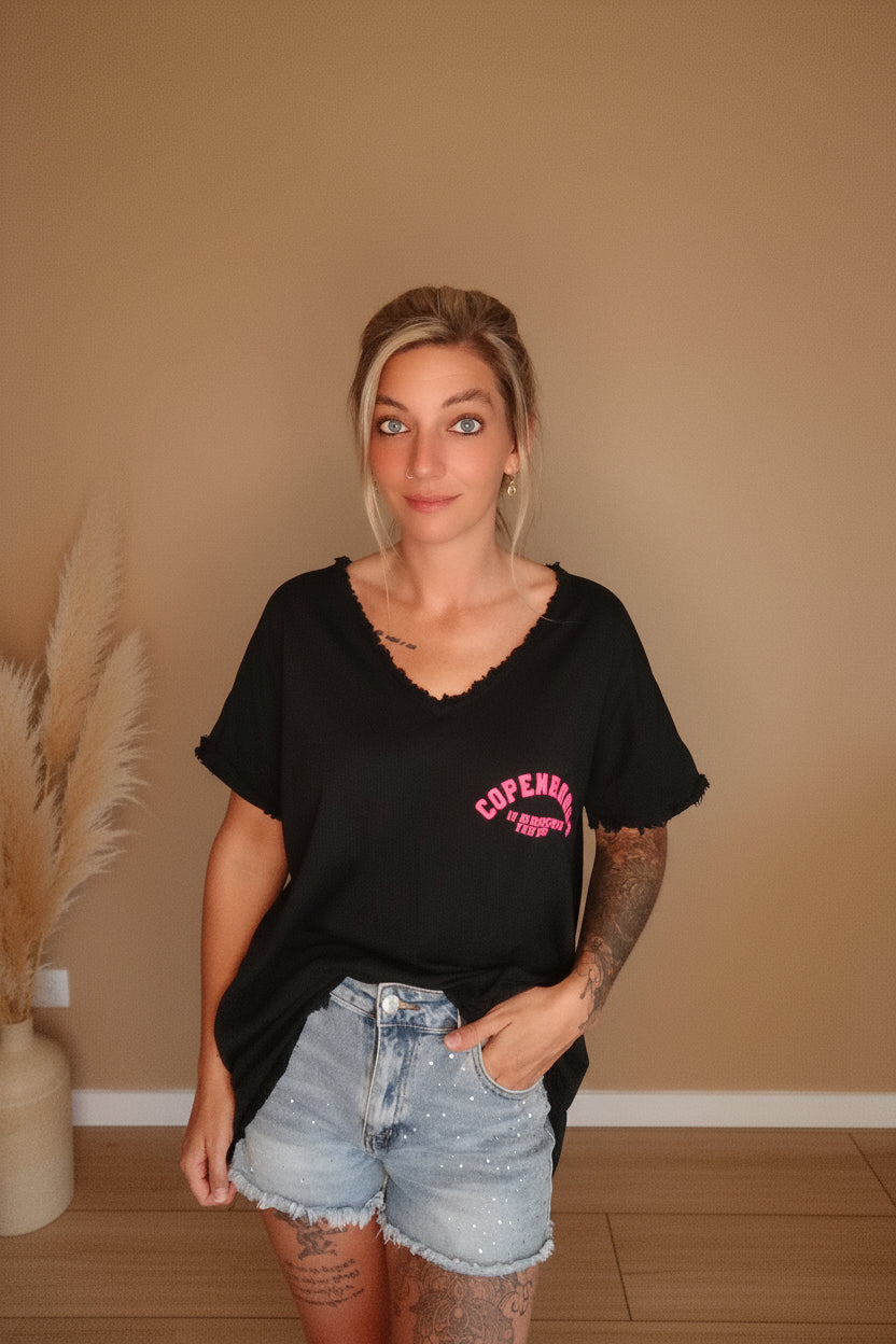 Boho-Luxe Look: Schwarzes Baumwoll-T-Shirt mit pinkem Print und hellblaue Jeans-Shorts.