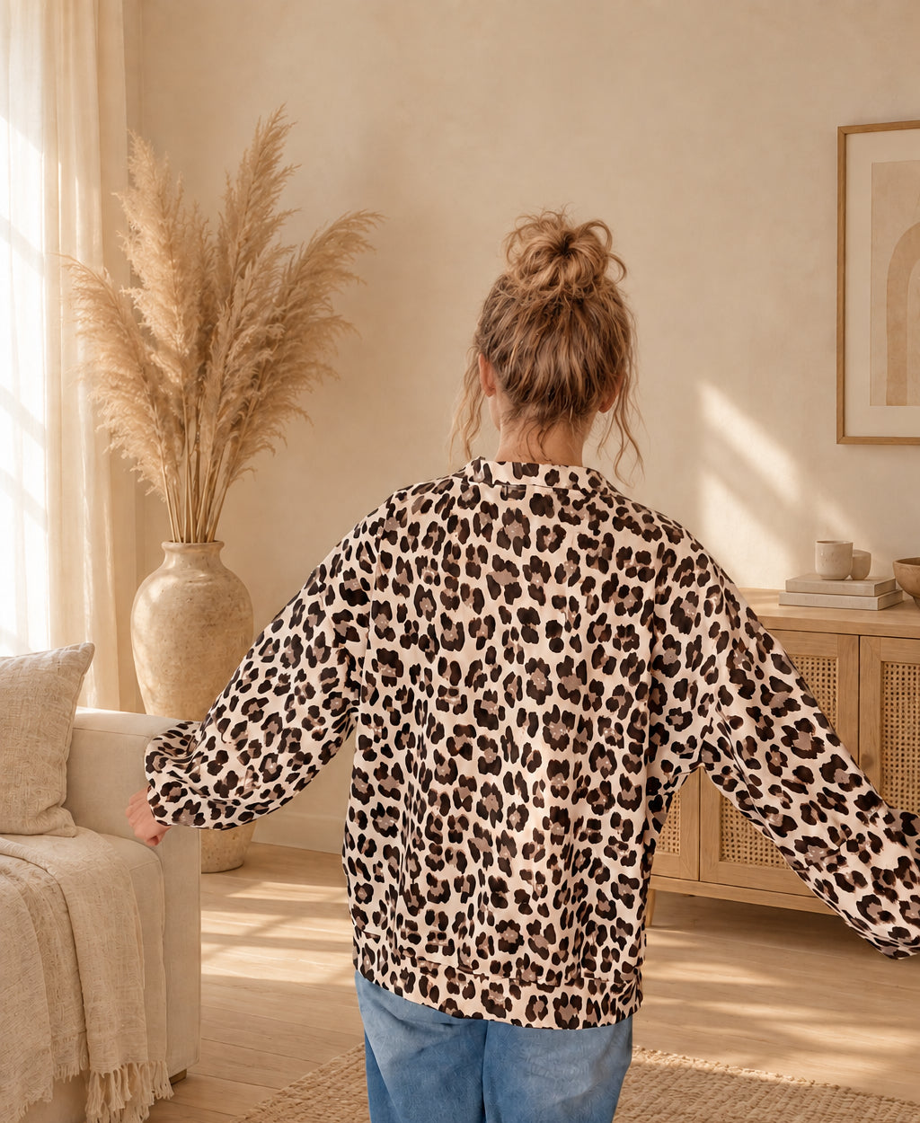 Rückansicht des Damen-Oberteils mit Leoprint, am Model mit seitlich ausgestreckten Armen und sichtbarem Saum.