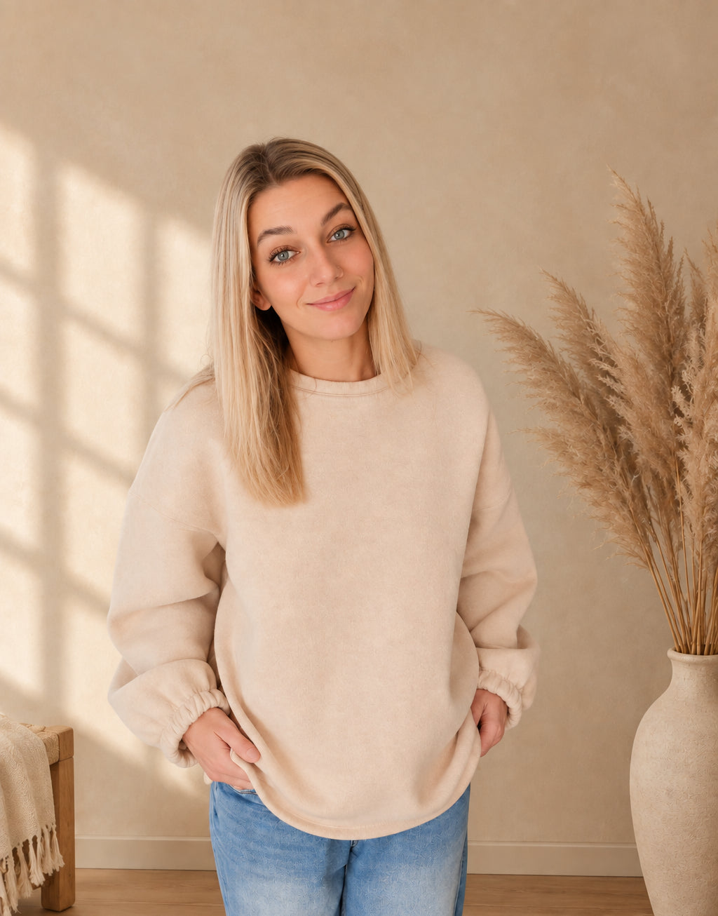 Cremefarbenes Oversize-Sweatshirt für Damen mit Rundhalsausschnitt und weiten langen Ärmeln, frontal zur Jeans getragen.