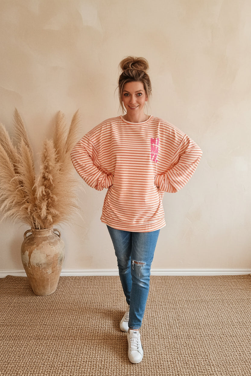Model trägt peach-weiß gestreiftes NAMASTE-Sweatshirt mit pinkem Frontprint