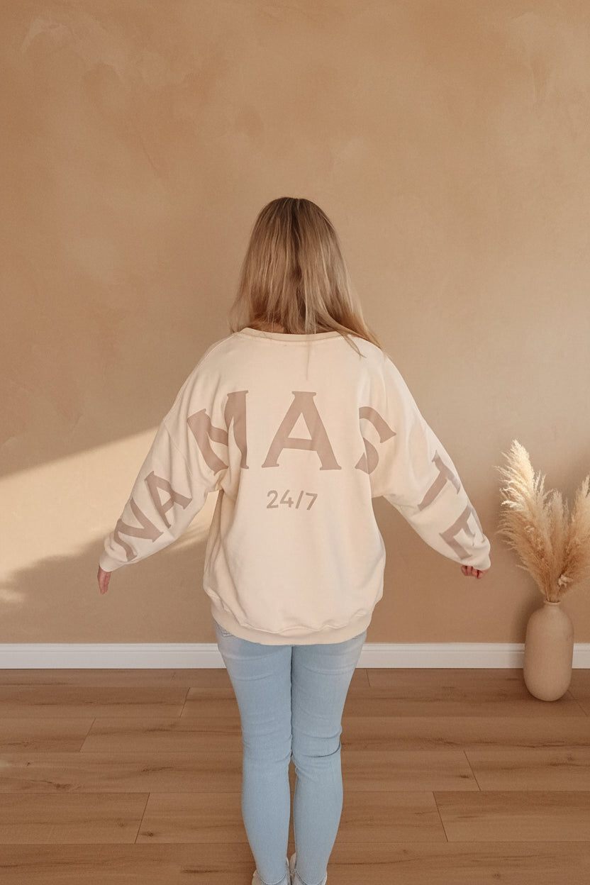 Namaste 24/7 Oversized Sweatshirt Creme – Rückenansicht im Sonnenlicht, Namaste 24/7-Schriftzug
